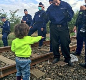 Προσφυγόπουλο προσφέρει ένα μπισκότο σε αστυνομικό στα σύνορα στην Ουγγαρία 